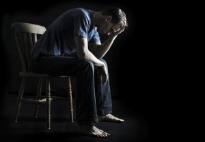 depressed or sad man sitting on chair in the dark